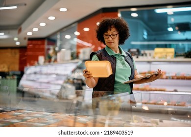 Supermarket worker checking labels while storing food in the freezer.  - Powered by Shutterstock