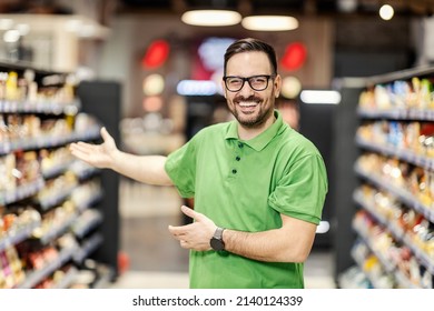 Supermarket Worker Greeting Customers. People At Work.