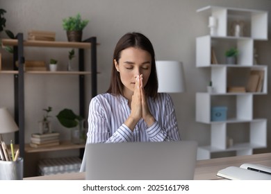 Superstitious Millennial Caucasian Woman Work On Computer Hold Hands In Prayer Ask Beg For Good Best Outcome Or Result. Religious Young Businesswoman Pray At Workplace. Faith, Religion Concept.