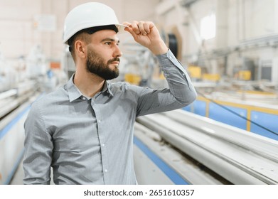 Supervisor adjusting his hardhat while inspecting pvc window production line in a modern factory