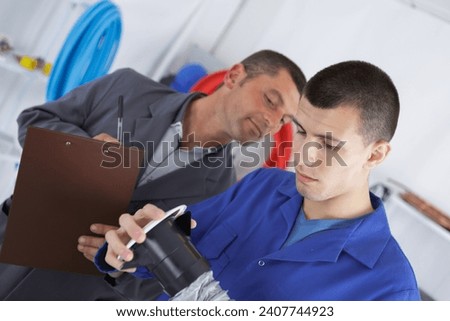 Supervisor assessing student assembling vetilation system