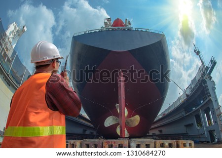 supervisor, foreman, inspector, surveyor takes final inspection of the cleaning, repairing, recondition of over hull of the commercial ship in dry dock yard, ready to delivery the ship to the sea