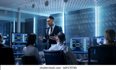 Supervisor Holds Briefing for His Employees in System Control Center Full of Monitors and Servers. Possibly Government Agency Conducts Investigation. 