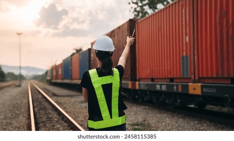 Supervisor inspecting inventory or task information on freight train cars and shipping containers. This pertains to logistics, including the import and export sectors.