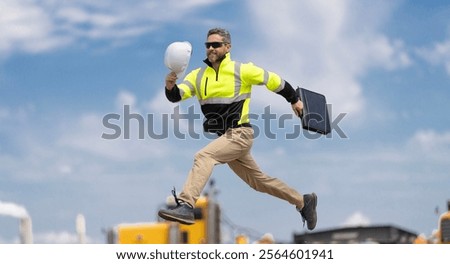 Supervisor jumping. Excited builder construction worker jumping in front of trucks. Man engineer running to success. Builder man run fast to work. Deadline. Engineer supervisor running outdoor