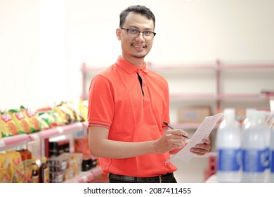 supervisor making notes to the clipboard while standing near a rack of mixed goods.
