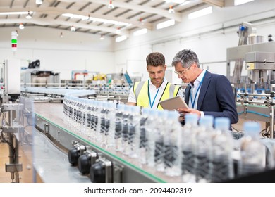 Supervisor and manager watching plastic bottles on conveyor belt - Powered by Shutterstock