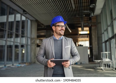 Supervisor Standing In Building In Construction Process, Holding Tablet And Checking On Works.