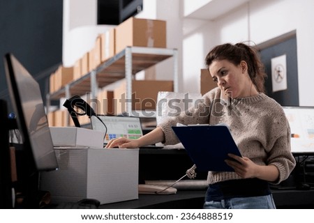 Supervisor talking at landline phone with remote manager, discussing merchandise inventory in stockroom. Storage room employee working at customers orders preparing shipping details