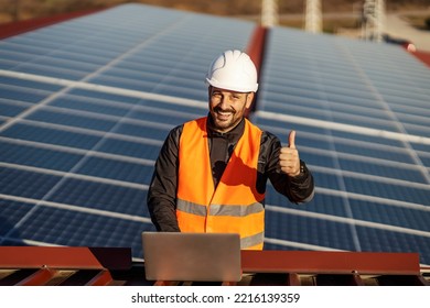 A supervisor is testing solar panels on the laptop and smiling at the camera while approving the test.