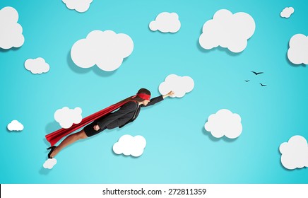 Superwoman In Red Mask And Cloak Flying Through Paper Clouds Over Blue Background