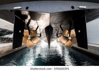 Superyacht being lowered into the water after winter haul out at shipyard, with freshly auti-fauled hull and polished propellers about to touch the water 
