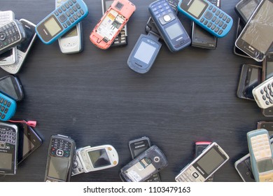 SUPHANBURI, THAILAND - JUNE 2, 2018: Many old mobile phones are technologically outdated, Unwanted mobile phone on black wood floor.