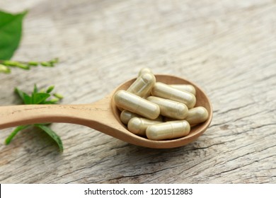 Supplement herbal capsules on wooden spoon with herb in kitchen table, healthy eating food for good life 