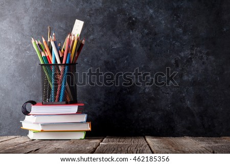 Supplies over notepads in front of chalk board. Back to school concept with copy space