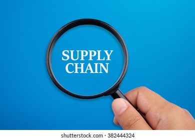 Supply chain. Hand holding magnifying glass focusing on the words.