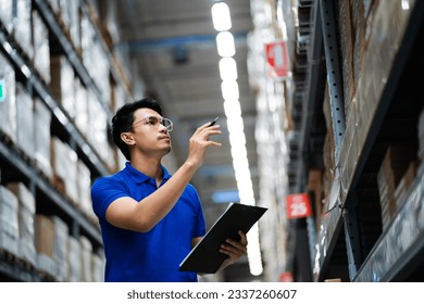 supply chain and logistic network technology concept. Happy Asian worker in blue uniform with clipboard in warehouse. Happy workers in the distribution center. - Powered by Shutterstock