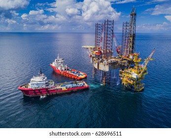 Supply Vessel Alongside Offshore Jack Up Drilling Rig Over The Production Platform in The Middle of The Sea
