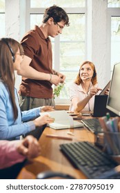 Support agents discussing tablet and client service in office. Concept of helpdesk training, customer care workflow, online support, team communication, and business consulting.