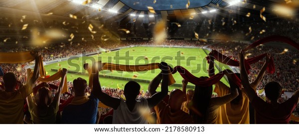 Support. Back\
view of football, soccer fans cheering their team with colorful\
scarfs at crowded stadium at evening time. Concept of sport, cup,\
world, team, event,\
competition