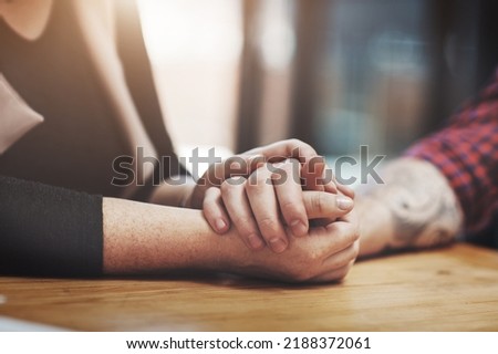 Support, compassion and trust while holding hands and sitting together at a table. Closeup of a loving, caring and affectionate couple comforting and helping each other through a difficult time