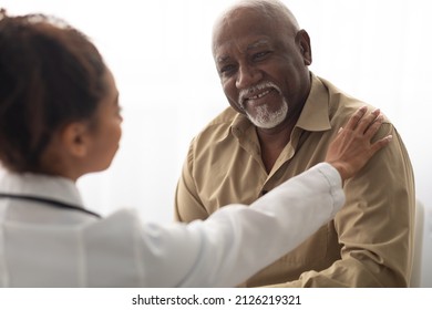 Support Concept. Closeup of black female doctor tapping patting patient's shoulder for empathy and encouragement during appointment in clinic. General practitioner cheering mature man at office - Powered by Shutterstock