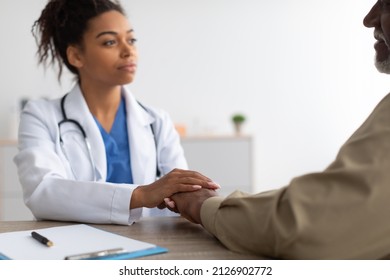 Support Concept. Closeup Of Black Female Doctor Holding Hands For Empathy And Encouragement During Appointment At Office In Clinic. General Practitioner Cheering Mature Man, Comforting Worried Patient