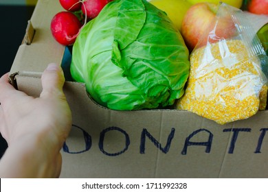 Support Food Banks During Coronavirus. COVID-19 Relief Funds And Donations. Volunteer In The Protective Medical Mask And Hand Gloves Holding Food Donation Box. Charity Donations