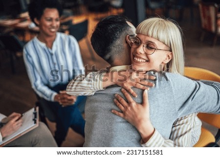 Support group patients hug each other during the therapy session. Group therapy session, addiction treatment or team building.