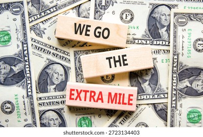 Support, help we go the extra mile symbol. Concept words We go the extra mile on beautiful wooden blocks. Beautiful dollar bills background. Business we go the extra mile concept. Copy space.