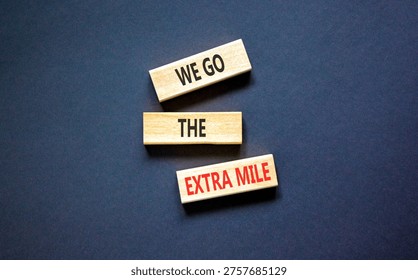 Support, help we go the extra mile symbol. Concept words We go the extra mile on beautiful wooden blocks. Beautiful black background. Business we go the extra mile concept. Copy space.