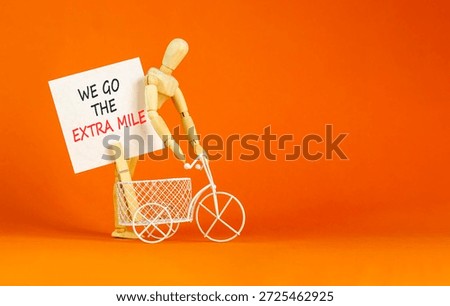 Support, help we go the extra mile symbol. Concept words We go the extra mile on beautiful white paper. Beautiful orange background. Miniature bicycle. Business we go the extra mile concept Copy space