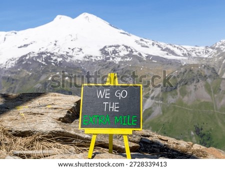 Support, help we go the extra mile symbol. Concept words We go the extra mile on beautiful blackboard. Beautiful mountain Elbrus background. Business we go the extra mile concept. Copy space.