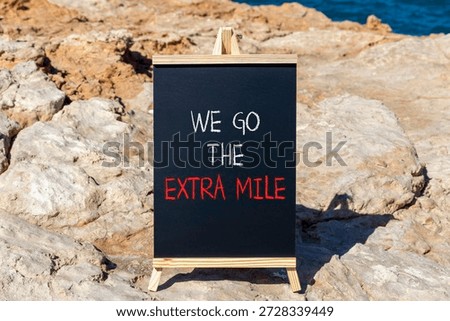 Support, help we go the extra mile symbol. Concept words We go the extra mile on beautiful blackboard. Beautiful stone and blue sky, sea background. Business we go the extra mile concept. Copy space.