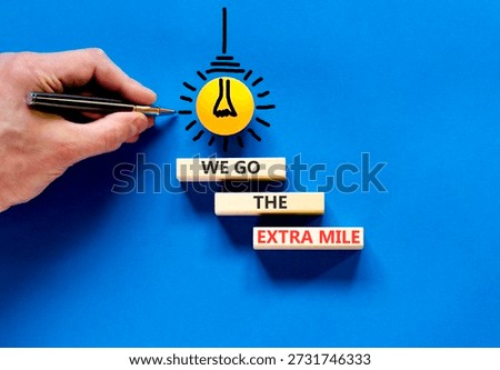 Support, help we go the extra mile symbol. Concept words We go the extra mile on beautiful wooden blocks. Beautiful blue background. Business we go the extra mile concept. Copy space.