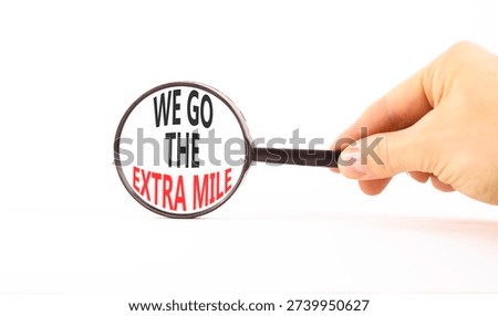 Support, help we go the extra mile symbol. Concept words We go the extra mile on magnifying glass. Businessman's hand. Beautiful white background. Business we go the extra mile concept. Copy space.