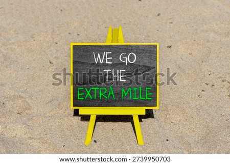 Support, help we go the extra mile symbol. Concept words We go the extra mile on beautiful blackboard. Beautiful sand beach background. Business we go the extra mile concept. Copy space.