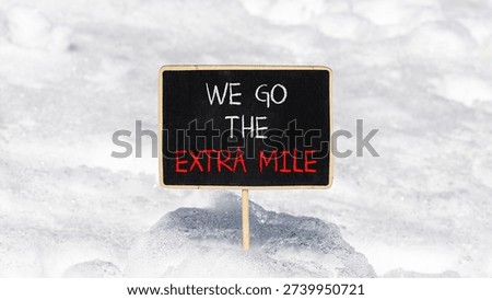 Support, help we go the extra mile symbol. Concept words We go the extra mile on beautiful blackboard. Beautiful white snow background. Business we go the extra mile concept. Copy space.