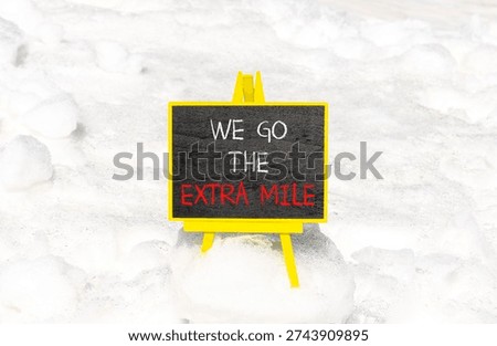 Support, help we go the extra mile symbol. Concept words We go the extra mile on beautiful blackboard. Beautiful white snow background. Business we go the extra mile concept. Copy space.