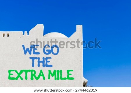 Support, help we go the extra mile symbol. Concept words We go the extra mile on beautiful white wall. Beautiful blue sky background. Business we go the extra mile concept. Copy space.