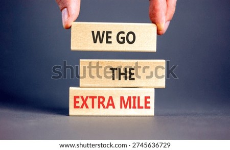 Support, help we go the extra mile symbol. Concept words We go the extra mile on beautiful wooden blocks. Beautiful grey background. Business we go the extra mile concept. Copy space.