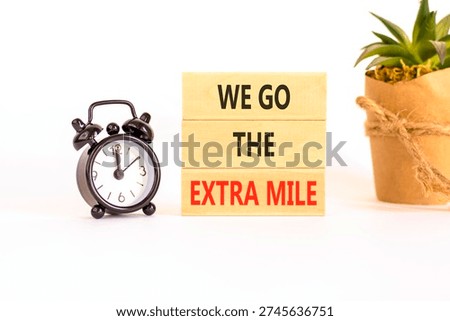Support, help we go the extra mile symbol. Concept words We go the extra mile on beautiful wooden blocks. Beautiful white background. Black alarm clock. Business we go extra mile concept. Copy space.