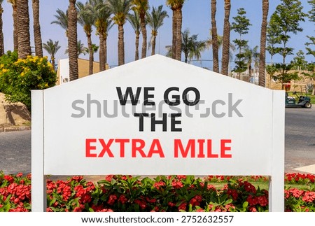 Support, help we go the extra mile symbol. Concept words We go the extra mile on beautiful white road sign. Beautiful palm trees blue sky background. Business we go the extra mile concept. Copy space.