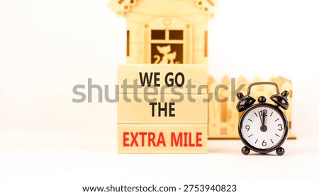 Support, help we go the extra mile symbol. Concept words We go the extra mile on beautiful wooden blocks. Beautiful white background. Black alarm clock. Business we go extra mile concept. Copy space.