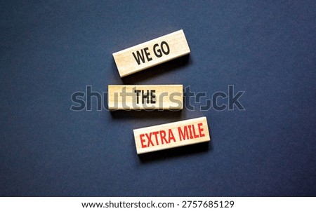 Support, help we go the extra mile symbol. Concept words We go the extra mile on beautiful wooden blocks. Beautiful black background. Business we go the extra mile concept. Copy space.