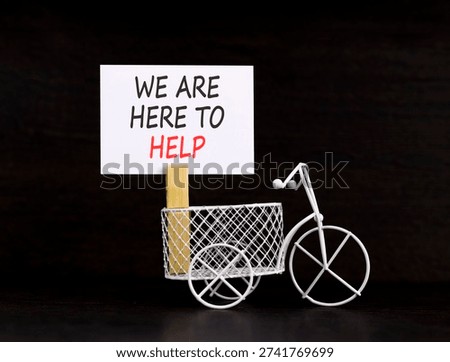 Support, help and we are here to help symbol. Concept words We are here to help on beautiful paper. Beautiful black background. Miniature bicycle. Business we are here to help concept. Copy space.