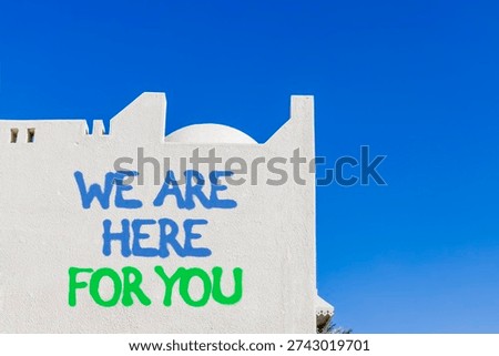 Support, help and we are here for you symbol. Concept words We are here for you on beautiful white wall. Beautiful blue sky background. Business we are here for you concept. Copy space.