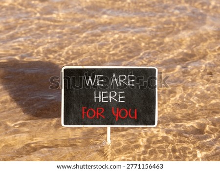 Support, help and we are here for you symbol. Concept words We are here for you on beautiful blackboard. Beautiful Red sea water background. Business we are here for you concept. Copy space.