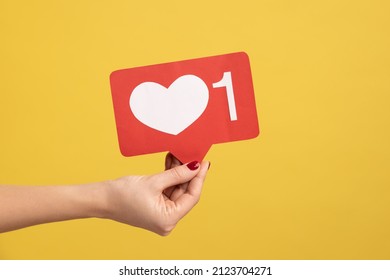 Support interesting web content, push heart button. Closeup of woman hand holding social media like icon, emoji sign to follow subscribe blog. Indoor studio shot isolated on yellow background. - Shutterstock ID 2123704271