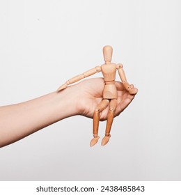 Support. A parent who provides support, attention, security to his child. Psychotherapy for adolescents. A hand holding a wooden mannequin in its palm. - Powered by Shutterstock